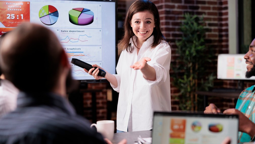 Directora comercial exponiendo a sus compañeros los resultados anuales en una presentación.