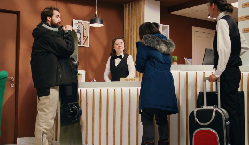 Recepcionista de hotel atendiendo a turistas extranjeros.